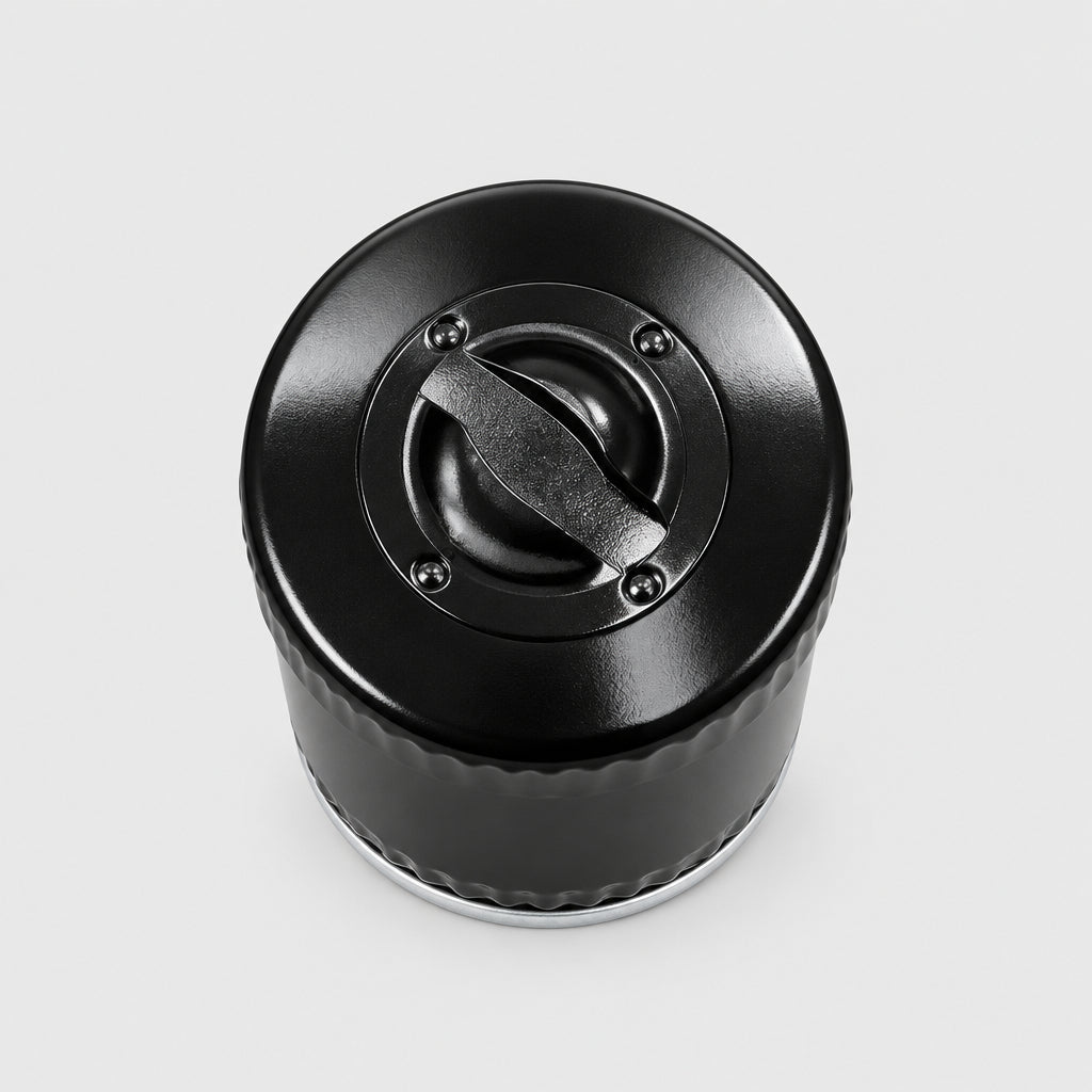 A close-up top-down view of a black plastic bottle cap or container lid placed on a light wood-grained tabletop.