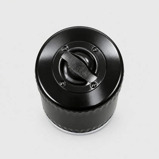A close-up top-down view of a black plastic bottle cap or container lid placed on a light wood-grained tabletop.